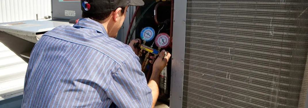 HVAC technician servicing a condenser unit in Aurora